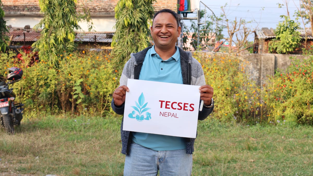 A man holding a TECSES sign and laughing.