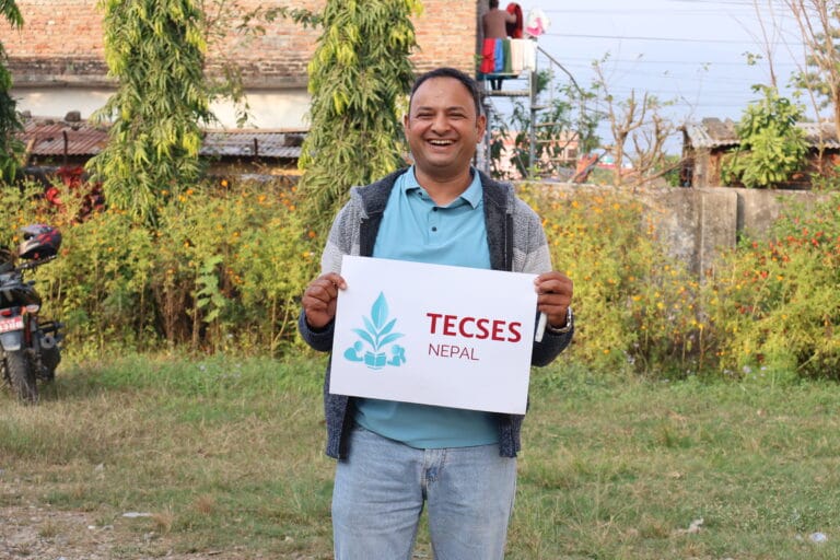 A smiling man holding up a TECSES sign