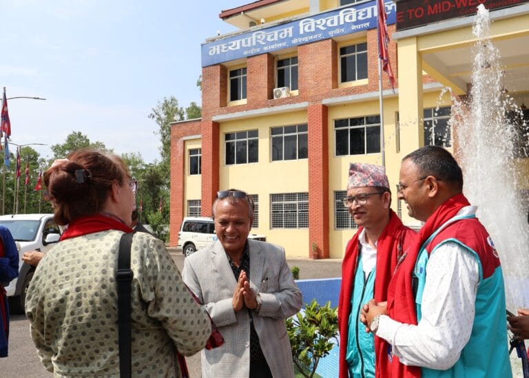 TECSES staff talking with Mid-West University staff member in front of a building